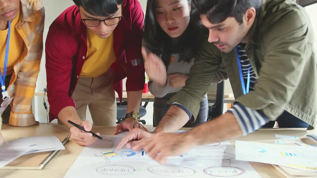 Meeting of UX developer and UI designer brainstorming about mobile app interface workflow design on table with coworker breif and color code at co-working space.Creative digital development agency.