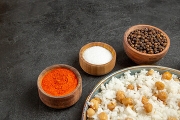 Half shot view of seasoned split peas and rice different spices mayonnaise and ketchup on dark table