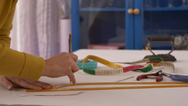 Closeup, Seamstress drawing lines on paper with set square triangle ruler