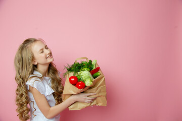 Cute girl on a pink background with vegetables