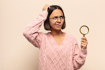 young hispanic woman feeling confused or doubting, concentrating on an idea, thinking hard, looking...