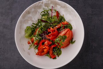 Vegan Spring Salad. Tomato, lettuce, dressing, bell peppers and avocados. Fork with vegetables and salad.