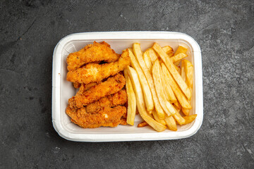 Overhead view of crispy fried chicken meal with potatoes on dark background