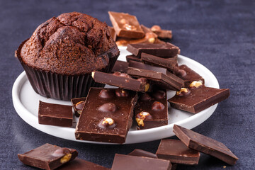 Chocolate cupcake with icing and chocolate bar in Dark lighting,Homemade delicious chocolate muffin on wooden background close-up