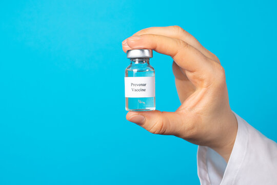 A doctor or laboratory technician keeps the Prevenar vaccine on a blue background. Vaccination against pneumocococy, prevention of pneumonia in infants