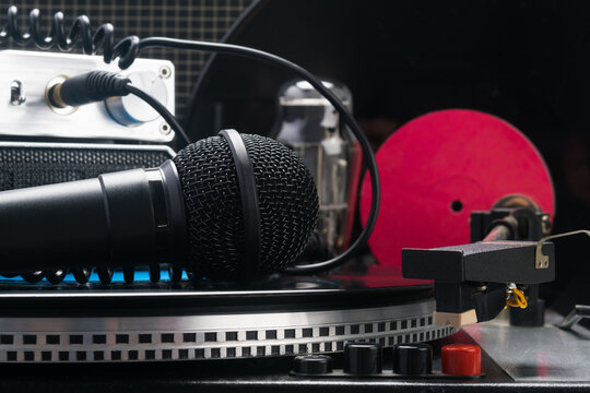 close-up of a microphone lying on a turntable against the backdrop of vinyl records