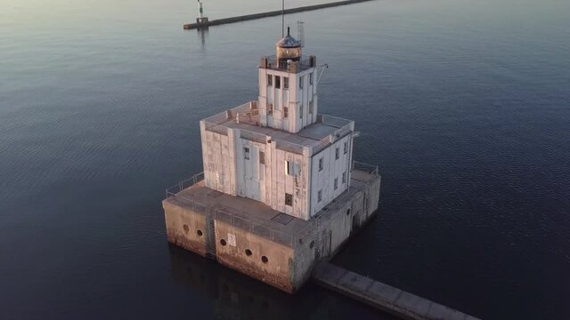 Stunning sunrise glowing over Lake Michigan harbor lighthouse on the coast of Milwaukee Wisconsin, establishing shot.
