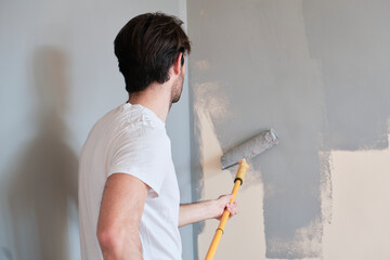 Young handsome man painting his walls