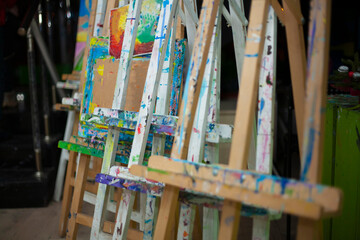 The easel is covered in paint. Artist's workplace. Multi-colored easel