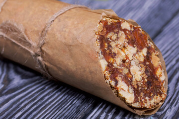 An energy bar made of dried fruits, nuts and seeds. Wrapped in edible paper. The wax seal is visible. On black pine boards.