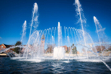 A beautiful fountain in a small city park with a brilliant blue sky.