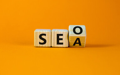 SEO vs SEA. Turned a cube and changed the word 'SEA - search engine advertising' to 'SEO - search engine optimization'. Business and SEO or SEA concept. Beautiful orange background, copy space.