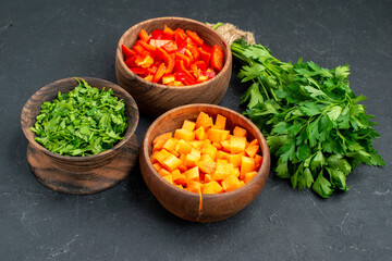 Dinner background with chopped vegetables and greens on dark background