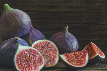 Cut and whole figs on dark, wooden background