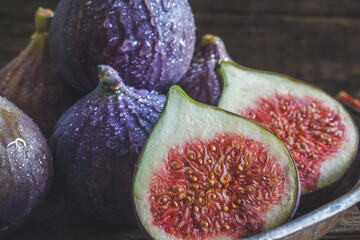 Cut and whole figs on dark, wooden background