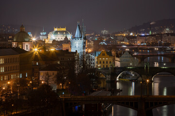 .view of the Vltava river and the bridges on it between them and the Charles Bridge and light from street lighting and the roofs of buildings in the center of Prague at night