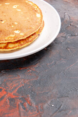 Half shot of American buttermilk pancakes on a white plate on mixed color background vertical view