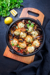 Traditional Norwegian fish ball fiskeboller with fish and mussels in red wine sauce as close-up in a modern design pot