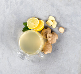 Drink tea lemon ginger with honey in a glass cup on a light gray background top view