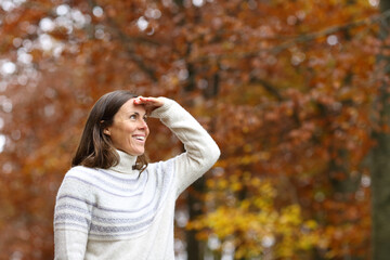 Happy adult woman searching in a forest in autumn