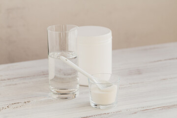 Hydrolyzed marine sourced collagen peptides in glass bowl and water on a white wooden background. Daily supplement concept.