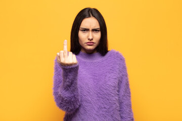 young hispanic woman feeling angry, annoyed, rebellious and aggressive, flipping the middle finger,...