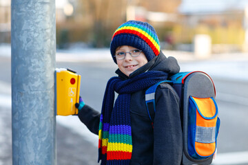 Little school kid boy of elementary class walking to school during snowfall. Happy healthy child...