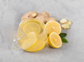 Tea lemon ginger in a glass cup on a light gray background