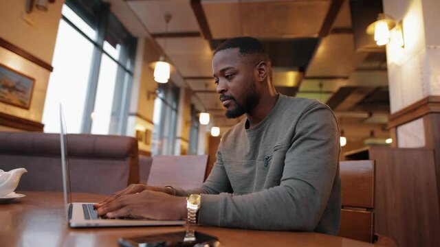 African American man opening laptop and working sitting in a cafe