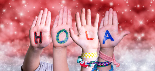 Children Hands Building Colorful Spanish Word Hola Means Hello. Red Snowy Christmas Winter Background With Snowflakes And Sparkling Lights © Nelos