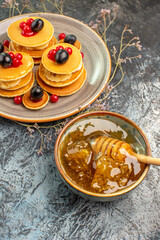 Vertical view of classic fruit pancakes and honey in a bowl