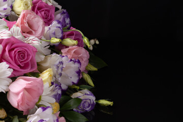 floral arrangement of roses, lisianthus, daisies, chrysanthemums on a black isolated background with free space for text.