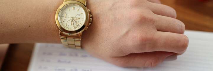 Woman's hand with watch pen next to it lies diary. Working time scheduling at remote work concept