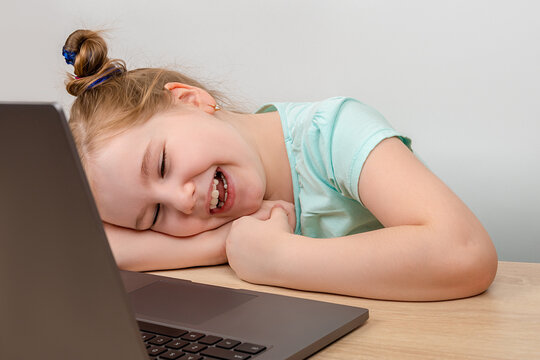 Distance learning online education. Laughing little girl using a laptop and speack via internet with her friends, relatives or teacher. New normal. Social distancing.