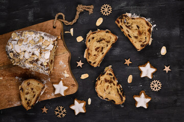 Slice of German Stollen cake, a fruit bread with nuts, spices, and dried fruits with powdered sugar traditionally served during Christmas time on dark background