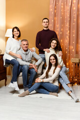 mom and dad are sitting in a chair. husband with wife and sister next to their parents. children and parents. new year holidays. Christmas. weekend with family