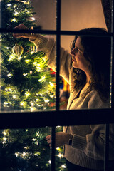 woman decorating christmas tree in the window