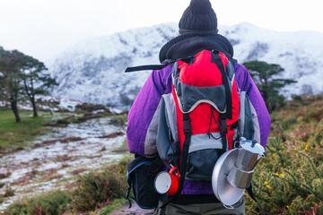 well-equipped mountaineer, with warm clothes, backpack and camping utensils, ascending a snowy mountain in winter. Mountain Sports.