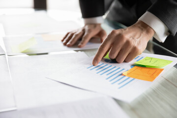 Crop close up of male bank employee or worker analyze financial paperwork in office boardroom. Busy focused businessman or man CEO work consider statistics on company document, plan business success.