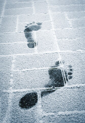 traces of bare feet on snowy pavement