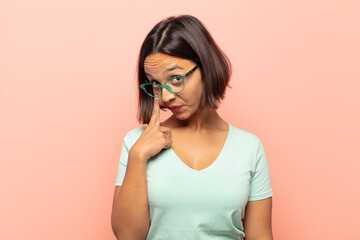 young hispanic woman keeping an eye on you, not trusting, watching and staying alert and vigilant