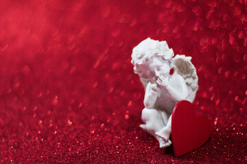 Cupid angel figurine on red background with bokeh, Valentine's Day and love and wedding