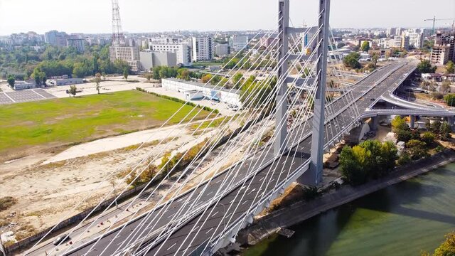 Ciurel passage, bridge over a river with moving cars, construction works, field and TV tower near it. Residential buildings on the background. View from the drone. Bucharest, Romania