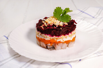 Traditional Russian herring under a fur coat on white plate with parsley. Rustic style. Christmas russian salad.
