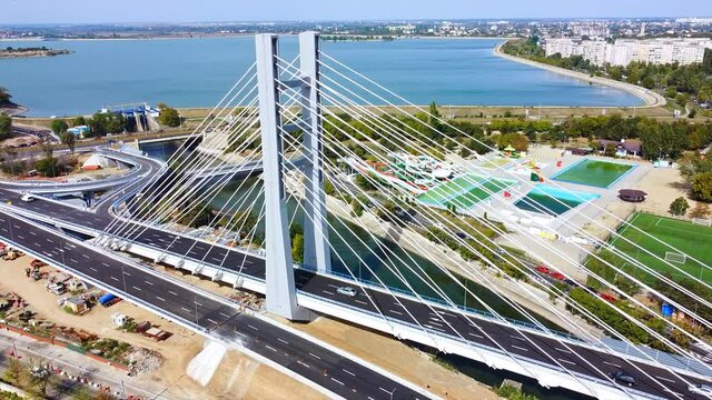 Ciurel passage, bridge over a river with moving cars, construction works, field and TV tower near it. Residential buildings on the background. View from the drone. Bucharest, Romania