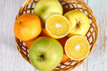 Top angle view on basket with fruit orange lemon and apples on table