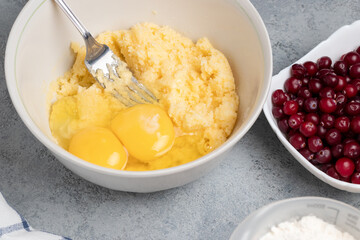 Making a dough for a sweet cranberry pie. Adding eggs