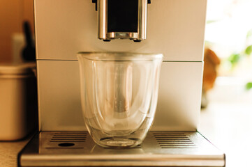 Brewing fresh coffee from the espresso machine. Preparing cappuccino in a glass transparent coffee cup.