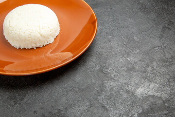 Half shot of view of steamed rice meal on a brown plate for dinner on dark background