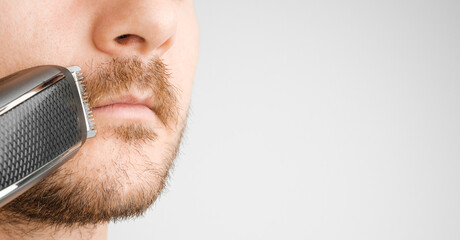 Shaving of mustache with electric razor or trimmer with copy space.